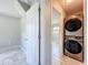 Modern laundry room featuring a stacked washer and dryer set and access to another room with tiled flooring at 9506 Number Two Rd, Howey In The Hills, FL 34737