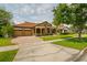 Single Gathering home featuring a three car garage, manicured lawn, stone accents, and mature trees at 9852 Caroline Park Dr, Orlando, FL 32832