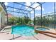 Sparkling screened-in pool and spa with views of the lake beyond the lush landscaping at 1070 Henley Downs Pl, Lake Mary, FL 32746
