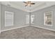 Spacious carpeted bedroom featuring tray ceilings and three windows with modern blinds at 14826 Deaton Aly, Orlando, FL 32827