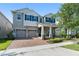 Two-story home with a brick driveway, 2-car garage and manicured lawn and blue shutters at 15420 Southern Martin St, Winter Garden, FL 34787