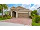 Inviting single-story home with manicured landscaping, a brick driveway, and a two-car garage at 15862 Citrus Grove Loop, Winter Garden, FL 34787