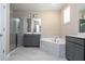 Elegant bathroom featuring gray cabinets, dual sinks, soaking tub, and glass-enclosed shower at 16103 Silver Brook Way, Winter Garden, FL 34787
