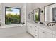 Bright bathroom featuring double sinks, modern fixtures, and a soaking tub with a garden view at 1891 Lake Spier Dr, Winter Park, FL 32789