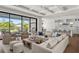 Bright living room featuring stylish seating, coffered ceiling, and sliding glass doors overlooking a beautiful lake at 1891 Lake Spier Dr, Winter Park, FL 32789