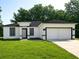 Charming one-story home boasts a manicured lawn, an attached garage, and a contemporary black-and-white facade at 2333 Sw 147Th Pl Rd, Ocala, FL 34473