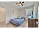 Neutral bedroom featuring a bed with a blue-patterned bedspread, wood floors, ceiling fan and an adjacent walk-in closet at 338 Wooded Vine Dr, Winter Springs, FL 32708