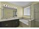 Bright bathroom showcasing a double vanity, a large mirror and bathtub with glass shower at 4051 Prairie Reserve Blvd, Orlando, FL 32824