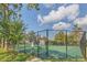 View of a well-maintained tennis court with lush green surface and chain link fence, nestled among trees at 485 Forestway Cir # 108, Altamonte Springs, FL 32701