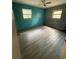 Bright bedroom featuring wood-look floors, fresh paint, and natural light from two windows at 605 Pleasantdale Dr, Wildwood, FL 34785