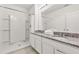 Bathroom with dual granite countertop sinks, white cabinets, and a shower with tile surround at 7041 Oakwood St, Davenport, FL 33837