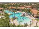 An aerial view of a community pool showcases amenities, palm trees, and gathering areas at 7041 Oakwood St, Davenport, FL 33837