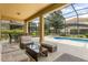 Relaxing covered patio with comfortable seating and an inviting view of the private pool and landscaped backyard at 7041 Oakwood St, Davenport, FL 33837