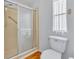 Bathroom with a glass shower door and a white toilet next to a window with lace curtains at 750 Polo Park Blvd, Davenport, FL 33897