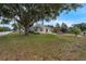 View of the home showing a large front yard with mature trees, well-kept lawn, and a decorative fountain at 803 Jersey Ave, St Cloud, FL 34769