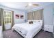 Sunny main bedroom with a large window, a bed, curtains, carpet and abstract floral paintings at 8919 Bismarck Palm Rd, Kissimmee, FL 34747