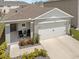 Home exterior featuring a two-car garage, a front porch with chairs, and manicured landscaping at 1323 Berry Ln, Davenport, FL 33837