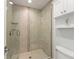 Tiled shower with glass door and wall niche, complemented by a built-in storage cabinet at 1455 Kelso Blvd, Windermere, FL 34786