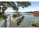 Dock featuring a boat house over the water with multiple boat slips and rope railings on a sunny day at 1455 Kelso Blvd, Windermere, FL 34786