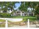 Beautiful property with solar panels on a lakeside lot featuring mature trees and a white retaining wall and black fencing at 1455 Kelso Blvd, Windermere, FL 34786