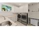 Bright laundry room featuring stainless steel washer and dryer, built in cabinets, countertops, and storage with a view to the outdoors at 1455 Kelso Blvd, Windermere, FL 34786