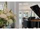 Elegant living room featuring a grand piano, hardwood floors, and water views at 1455 Kelso Blvd, Windermere, FL 34786