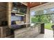 Granite outdoor kitchen, with grill, mini fridge and bar seating under a covered patio with lake views at 1455 Kelso Blvd, Windermere, FL 34786