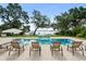 Beautiful in-ground swimming pool surrounded by mature trees and landscaping overlooking a serene lake at 1455 Kelso Blvd, Windermere, FL 34786