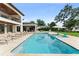 Back of house showcasing a large pool, lounge chairs, manicured lawn, and lake view at 1455 Kelso Blvd, Windermere, FL 34786