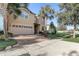 Lovely front exterior of a two-story home with a brick driveway, manicured lawn, and mature landscaping including palm trees at 2186 Tripoli Ct, Kissimmee, FL 34747