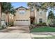 Charming two-story home with a brick driveway and a spacious two-car garage surrounded by lush landscaping and mature palm trees at 2186 Tripoli Ct, Kissimmee, FL 34747