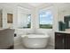 Bright bathroom with a standalone tub situated under large windows offering scenic outdoor views at 2586 Lancaster Ridge, Davenport, FL 33837