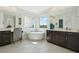 Stylish bathroom with a standalone tub positioned between dual vanities, providing ample space and light at 2586 Lancaster Ridge, Davenport, FL 33837