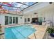 Screened in pool area with a cozy outdoor kitchen, outdoor seating, and an inviting pool and spa at 2586 Lancaster Ridge, Davenport, FL 33837