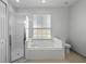 Bright bathroom features a glass enclosed shower and a soaking tub under a window at 548 Casterton Cir, Davenport, FL 33897