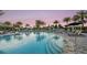 A luxurious pool with lounge chairs and umbrellas creates a relaxing oasis surrounded by palm trees at 5652 Nevis Ter, Kissimmee, FL 34758