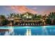 Stunning view of the community pool and clubhouse with palm trees against a vibrant sunset sky at 5658 Nevis Ter, Kissimmee, FL 34758
