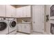 Bright laundry room featuring modern washer and dryer, ample white cabinetry, and stylish backsplash at 5658 Nevis Ter, Kissimmee, FL 34758