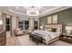 Beautifully staged main bedroom featuring a tray ceiling, elegant chandelier, wainscoting, and ample natural light at 5658 Nevis Ter, Kissimmee, FL 34758
