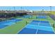 Aerial view of multiple pickleball courts with vibrant blue and green surfaces, surrounded by lush landscapes at 5658 Nevis Ter, Kissimmee, FL 34758