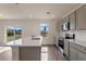Bright kitchen features stainless appliances, gray cabinets, an island, and sliding glass door to the backyard at 5896 Galloping Dr, Apopka, FL 32712