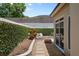 Backyard view with lush green hedge, decorative rocks, and brick paver patio near exterior wall at 5973 Chesapeake Park # 58, Orlando, FL 32819