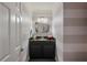 Stylish powder room featuring striped walls, a decorative mirror, and a sleek vanity enhancing the home's charm at 5973 Chesapeake Park # 58, Orlando, FL 32819