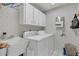 A functional laundry room is equipped with washer, dryer, and storage cabinets at 605 Macglenross Dr, Oviedo, FL 32765