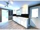 Modern kitchen featuring white cabinets, black backsplash, stainless steel appliances, and wood-look tile flooring at 6615 Beamer Way, Orlando, FL 32807