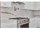 Close-up of the gourmet kitchen featuring an industrial gas range, custom vent hood, and designer backsplash at 734 Terra Pl, Maitland, FL 32751