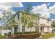 Two-story townhome showcasing manicured bushes and multi-pane windows under a partly cloudy sky at 87 Delacorte Way, Oviedo, FL 32765
