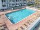 Large rectangular swimming pool with chairs surrounded by red brick and fencing at 935 S Atlantic Ave # 355, Daytona Beach, FL 32118