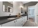 Bathroom with double sinks, white cabinets, and an open doorway to a bedroom at 10100 Loblolly Pine Cir, Orlando, FL 32827