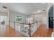 Upstairs hallway with hardwood flooring and a railing overlooking the living room and kitchen at 10100 Loblolly Pine Cir, Orlando, FL 32827